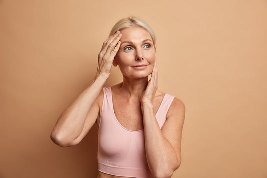 Vrouw met gezonde huid raakt haar gezicht aan als symbool voor huidverzorging en collageenproductie – illustratie bij blog over wat is collageen.