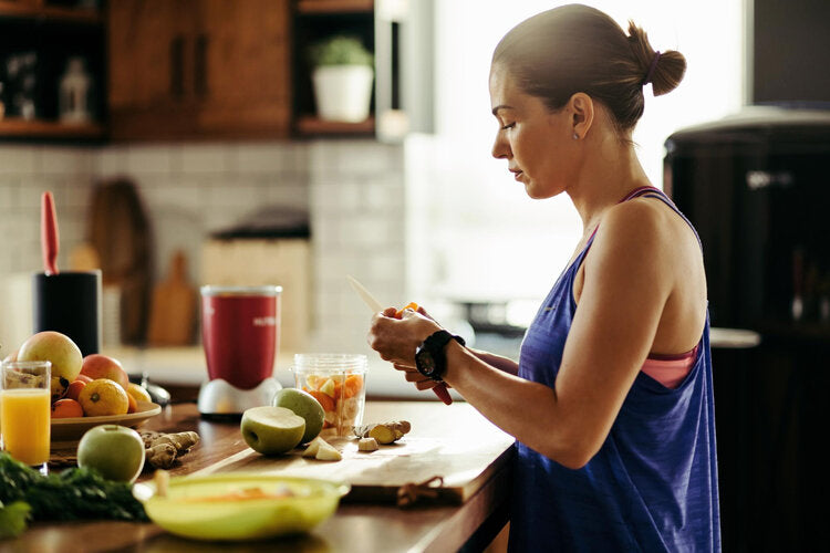 Wat eten voor het sporten: vrouw bereidt een gezonde maaltijd met vers fruit voor een training.